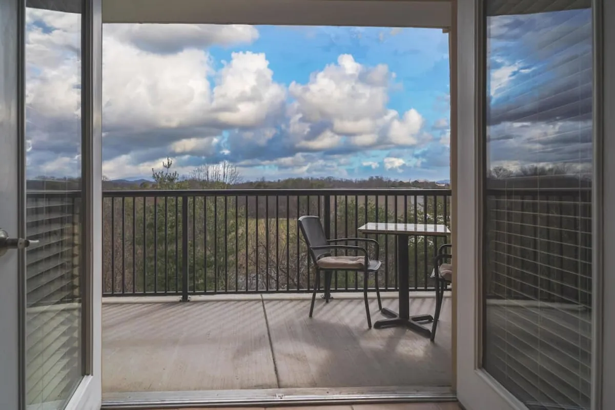 An exterior balcony scene featuring a table and chairs set against a scenic backdrop. It suggests a relaxed environment where families can gather for morning coffee, conversation, or enjoy the sunset together.