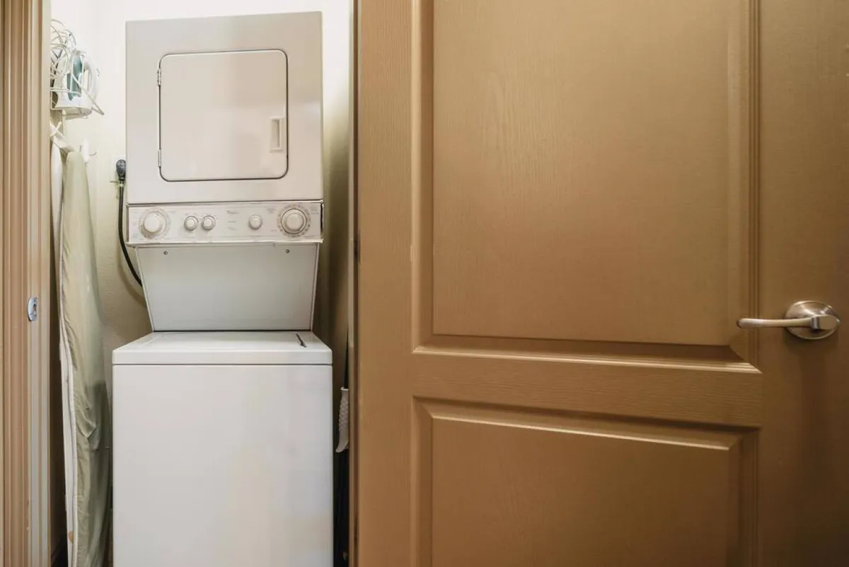 A laundry nook with a stacked washer and dryer, surrounded by organized laundry supplies, providing a practical and essential amenity for longer stays.